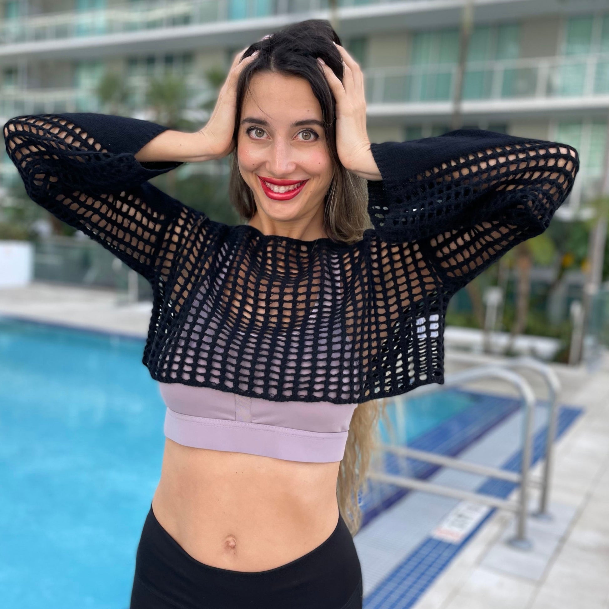 Black solid hollow knit crochet boho sweater top by the pool.